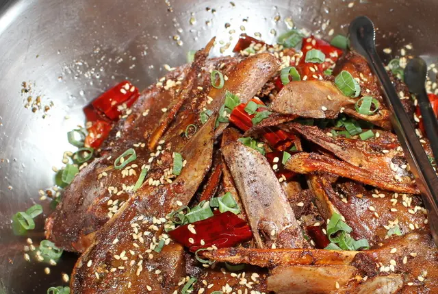 來自大陸的口味鴨頭，先以滷汁滷透，加醬料炒香，再灑上花椒，淋上多種藥材泡製的熱油嗆香。