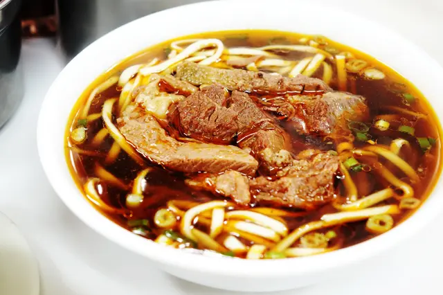 深褐色的湯頭帶著點點辣紅油浮在上面,嚼一口,鹹中帶點微辣;厚厚的牛肉嫩口非常,有的更帶著絲絲牛根