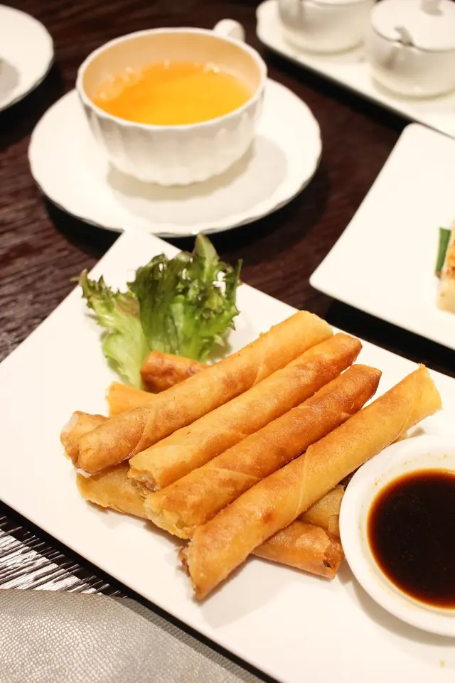 長春捲堆砌在晶瑩剔透的玻璃杯中，長條狀外觀似脆迪酥